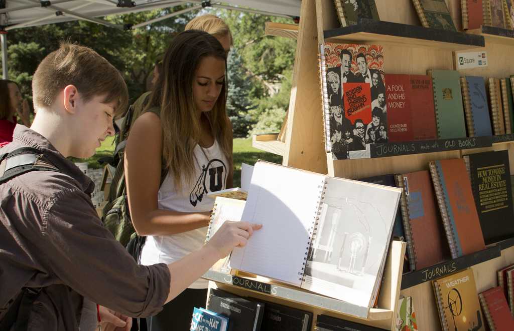 Students browse a book stand during the first farmers market of the school year at Tanner Plaza, Thursday August 27, 2015.