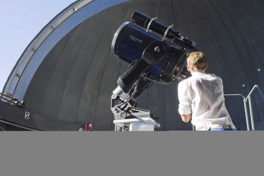 High school student Grant Amann peers through a telescope in the observatory atop the astronomy building this Saturday as a part of the U Science Day activities. Josh Anderson