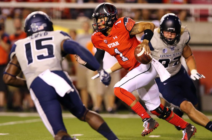 Senior quarterback Kendal Thompson (1) runs between two defenders during a football game against the Utah State Aggies at Rice Eccles Stadium, Friday, Sept. 11, 2015. Dane Goodwin, Daily Utah Chronicle.