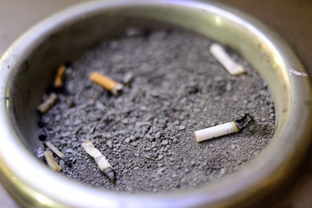 Cigarette+butts+in+a+smoking+disposal+on+top+of+a+garbage+can+on+campus+Monday%2C+Sept.+14%2C+2015