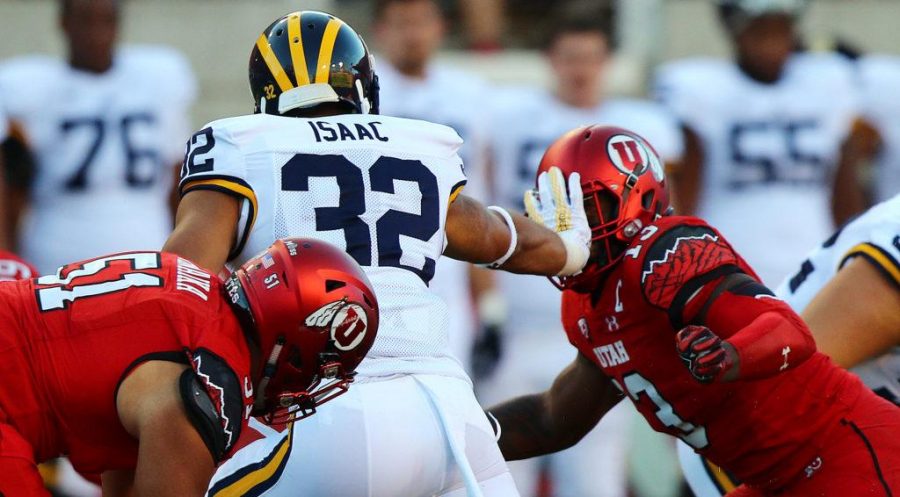 Michigan Wolverines running back Ty Smith (32) reaches up to stiff-arm senior linebacker Gionni Paul (13) in the first half against the Michigan Wolverines at Rice-Eccles Stadium, Thursday, September 3, 2015. Utah won the contest, 24-17. Chris Samuels, Daily Utah Chronicle.