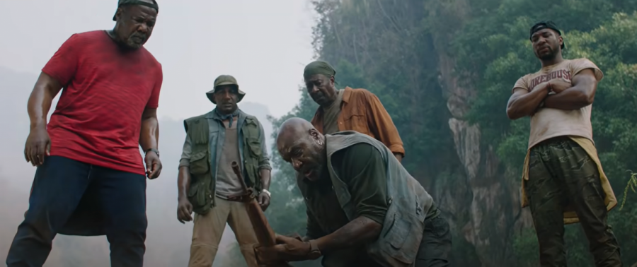 The Bloods gather around the rifle of their fallen squad leader in Da 5 Bloods. (Courtesy Netflix) 