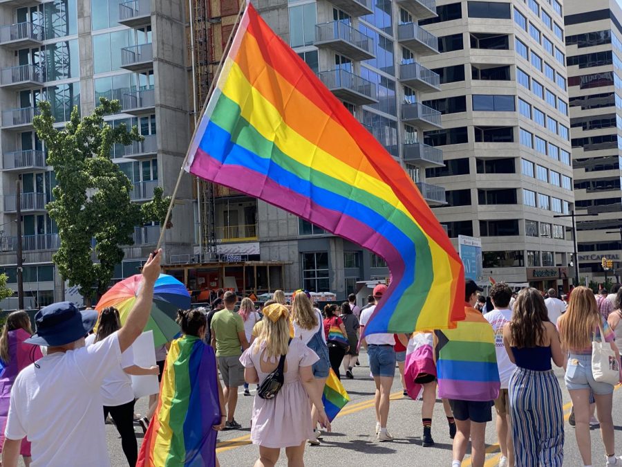 A pride flag is held high as marchers proceed down State St. in Salt Lake City for the Pride march on June 6, 2021. (Photo by Jack Gambassi | The Daily Utah Chronicle)