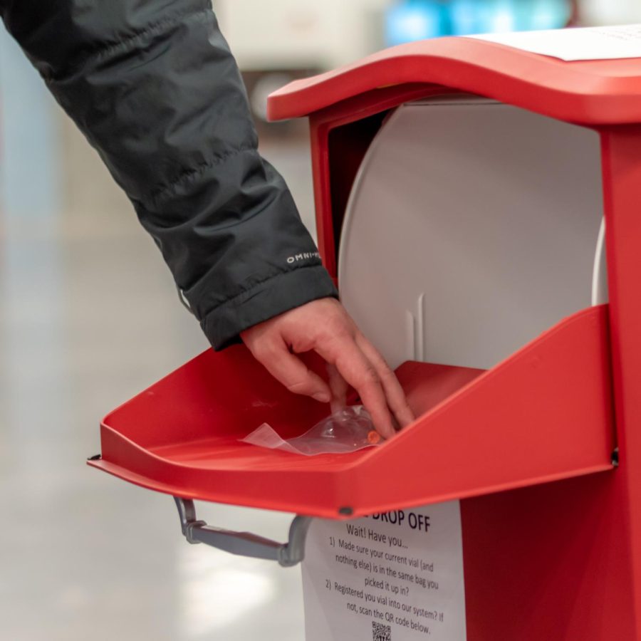 A member of the U of U campus community deposits a Covid-19 self-test sample in a collection box inside of Kahlert Village on campus in Salt Lake City on Friday, Feb 4, 2022. (Photo by Jack Gambassi | The Daily Utah Chronicle)
