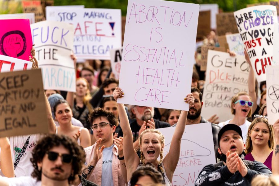 A demonstrator holds a sign that reads "Abortion is essential health care" at the protest against the potential overturn of Roe v. Wade at the Utah State Capitol on May 5, 2022. (Photo by Xiangyao "Axe" Tang | The Daily Utah Chronicle)