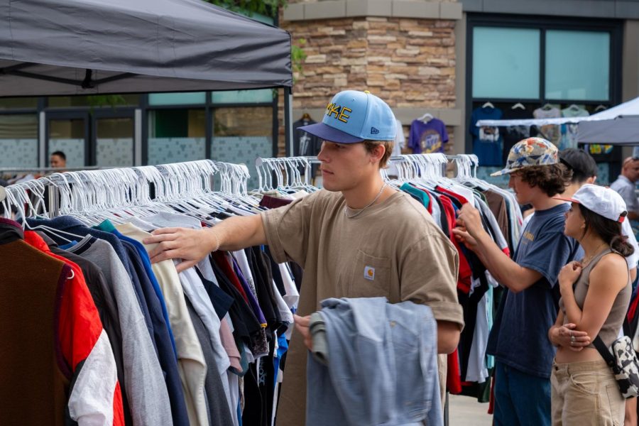 Market-goers peruse the contents of clothes racks during the Urban Flea Market at The Gateway in Salt Lake City on Sunday, June 11, 2023.