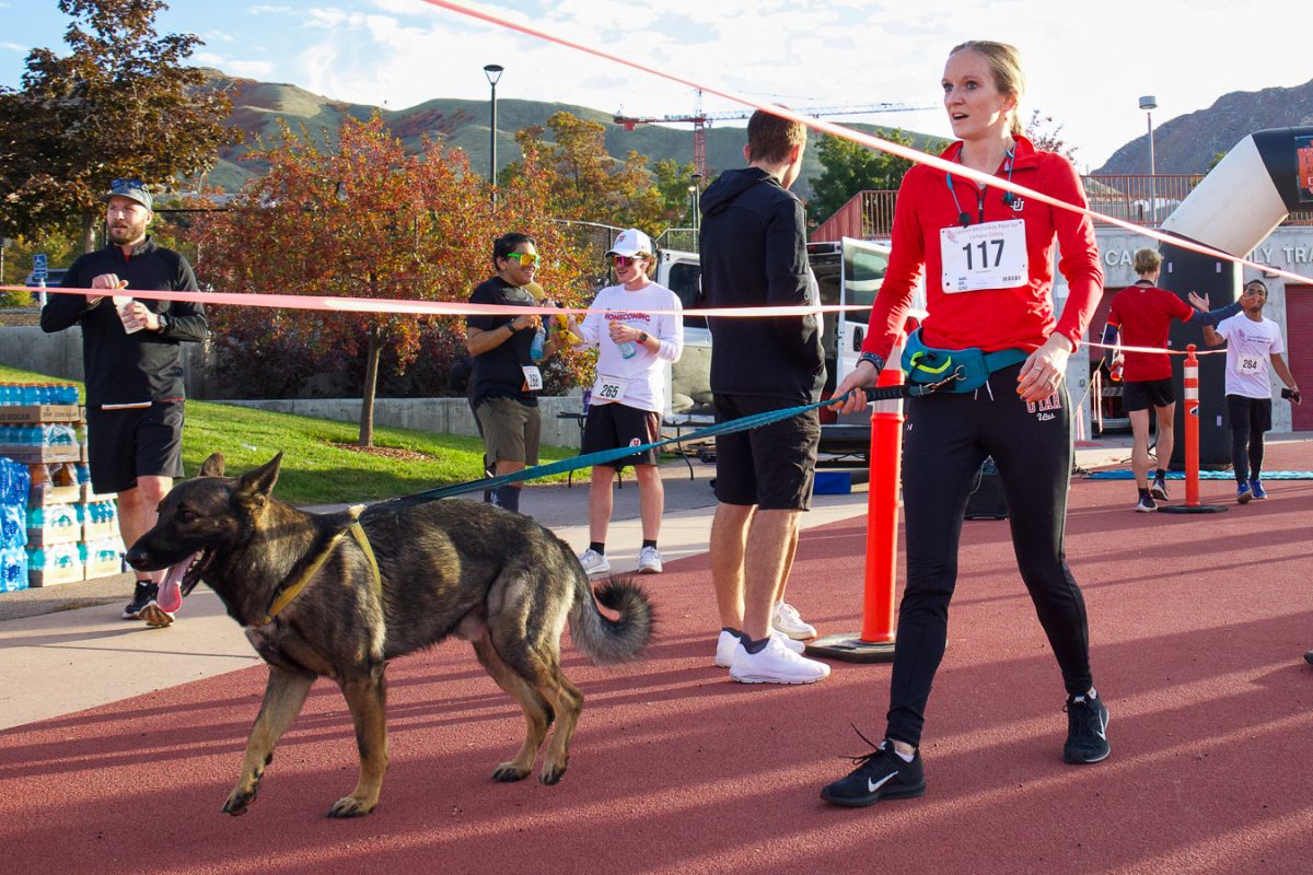 A participant with a dog companion at the finish line of the 2nd Annual Race for Campus Safety at McCarthey Family Track & Field Complex in Salt Lake City on Saturday, Oct. 21, 2023. (Photo by Minh “Polaris” Vuong | The Daily Utah Chronicle)