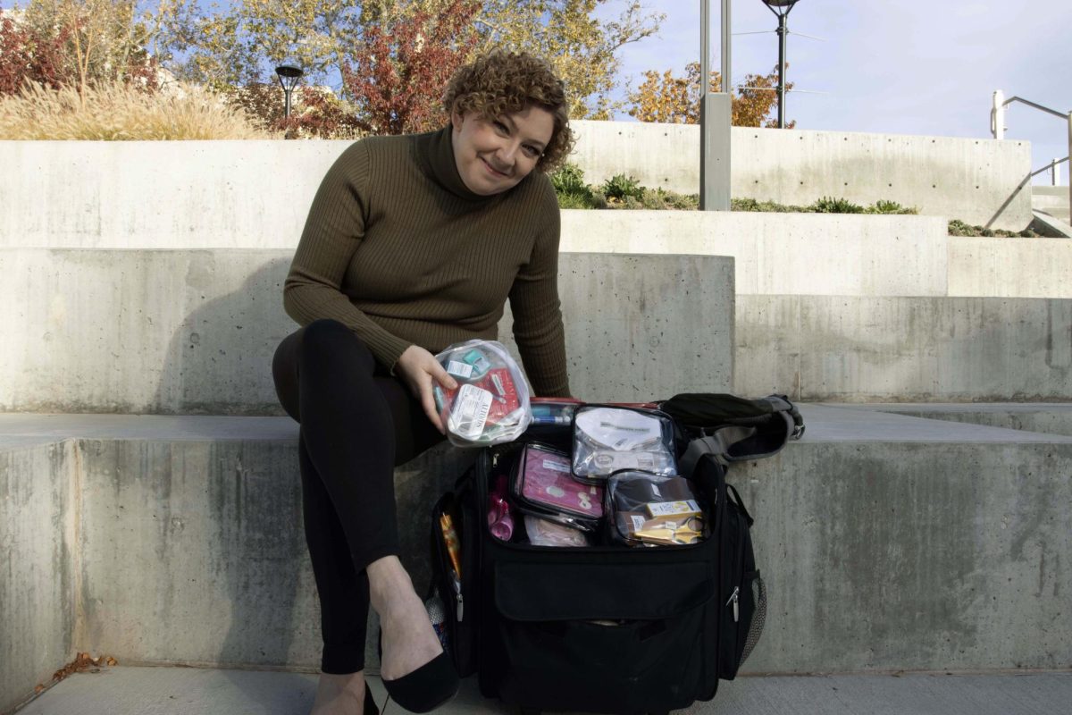 Liz Whittaker poses for a photo with her intimacy supply bag outside the Price Theatre Arts Building on Nov. 5, 2023. (Photo by Sarah Karr | The Daily Utah Chronicle)