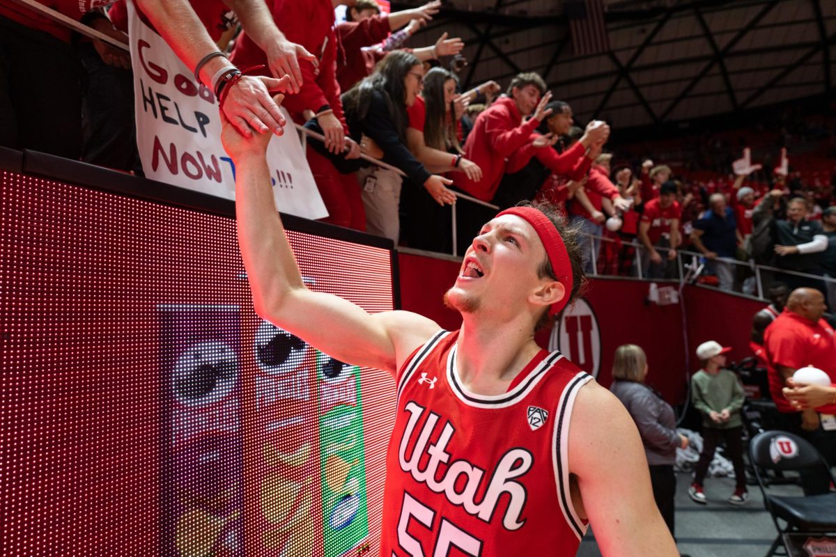 Utah guard Gabe Madsen (55) high-fives fans after defeating the BYU Cougars at the Jon M. Huntsman Center in Salt Lake City on Saturday, Dec. 9, 2023. (Photo by Xiangyao “Axe” Tang | The Daily Utah Chronicle)