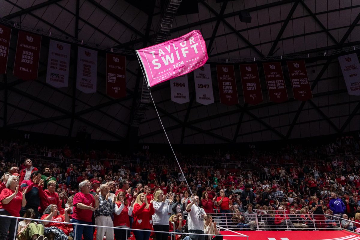 A Utah Red Rocks fan swings a Taylor Swift flag in the meet versus the Stanford Cardinal at the Jon M. Huntsman Center in Salt Lake City on Friday, Feb. 23, 2024. (Photo by Xiangyao “Axe” Tang | The Daily Utah Chronicle)
