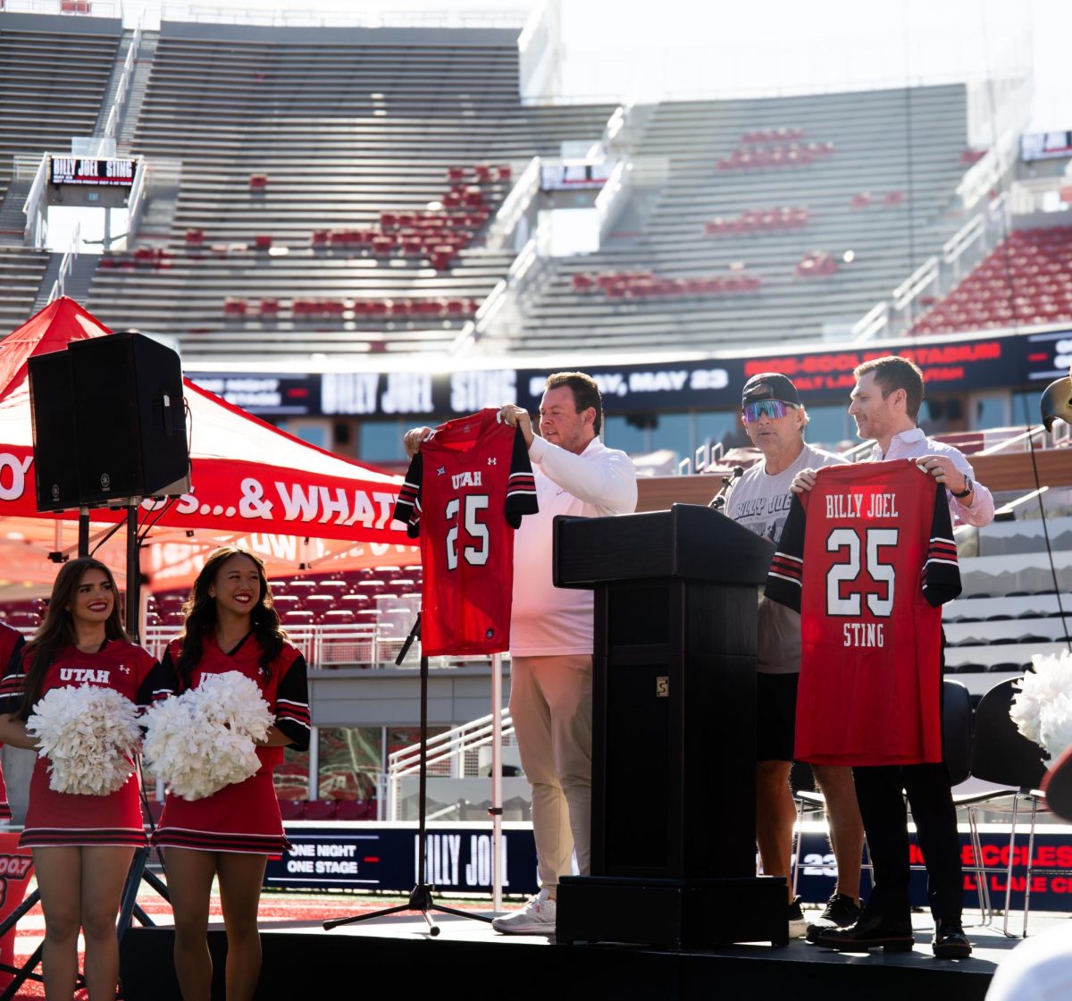 University of Utah Athletics Director Bill Riley holds a jersey alongside Utah Football Head Coach Kyle Whittingham and Live Nation Utah President Jason Farrell, while Whittingham talks about being excited for the concert. (Photo by Addy Cowley | The Daily Utah Chronicle)