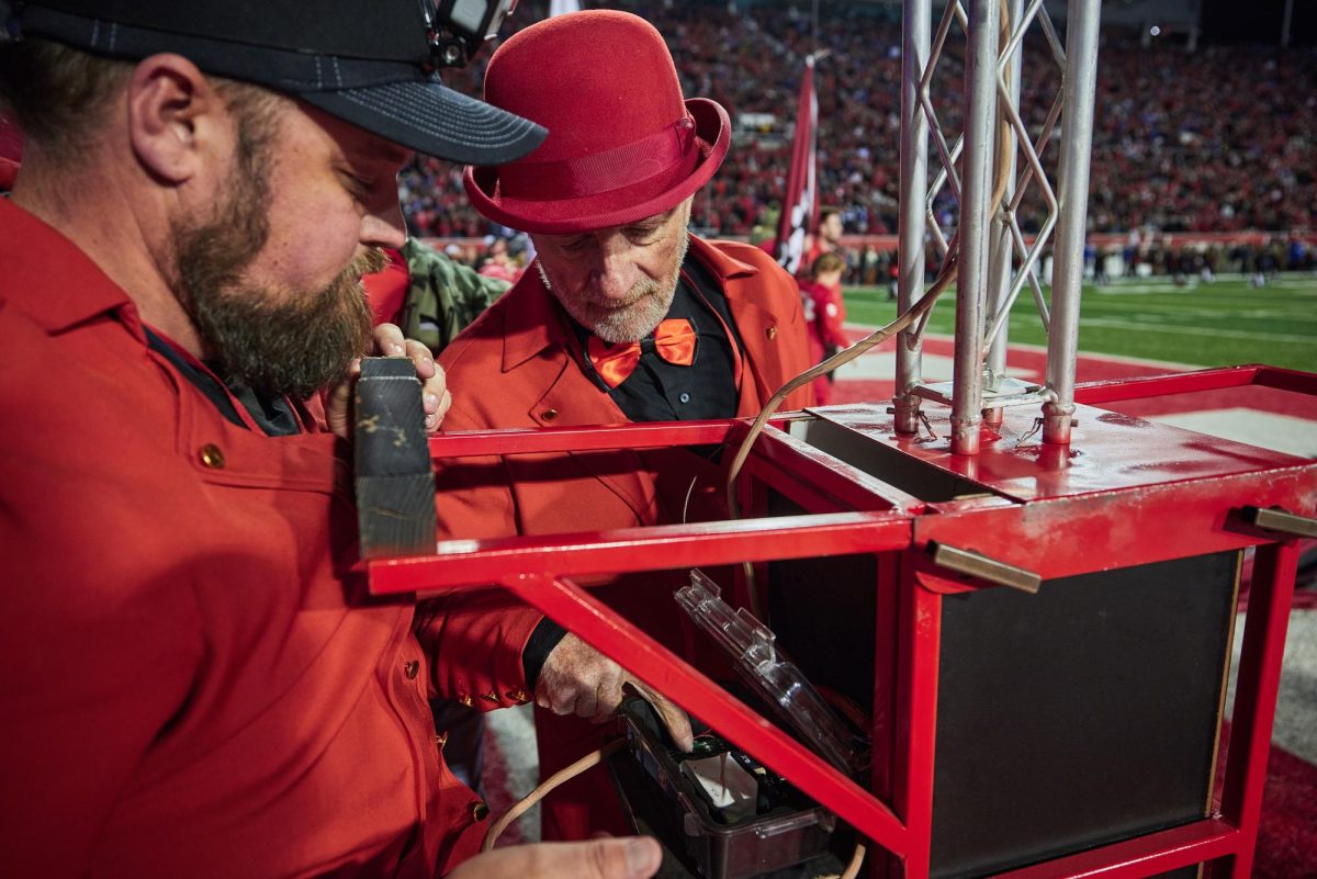 Brady Gabbitas (Left) and Chuck Johnson (center) inspect a radio receiver connected to a flare before the Utah Utes run on of the U vs. BYU game in the Rice-Eccles Stadium on Saturday, Nov. 9, 2024. (Photo by Luke Larsen | The Daily Utah Chronicle)