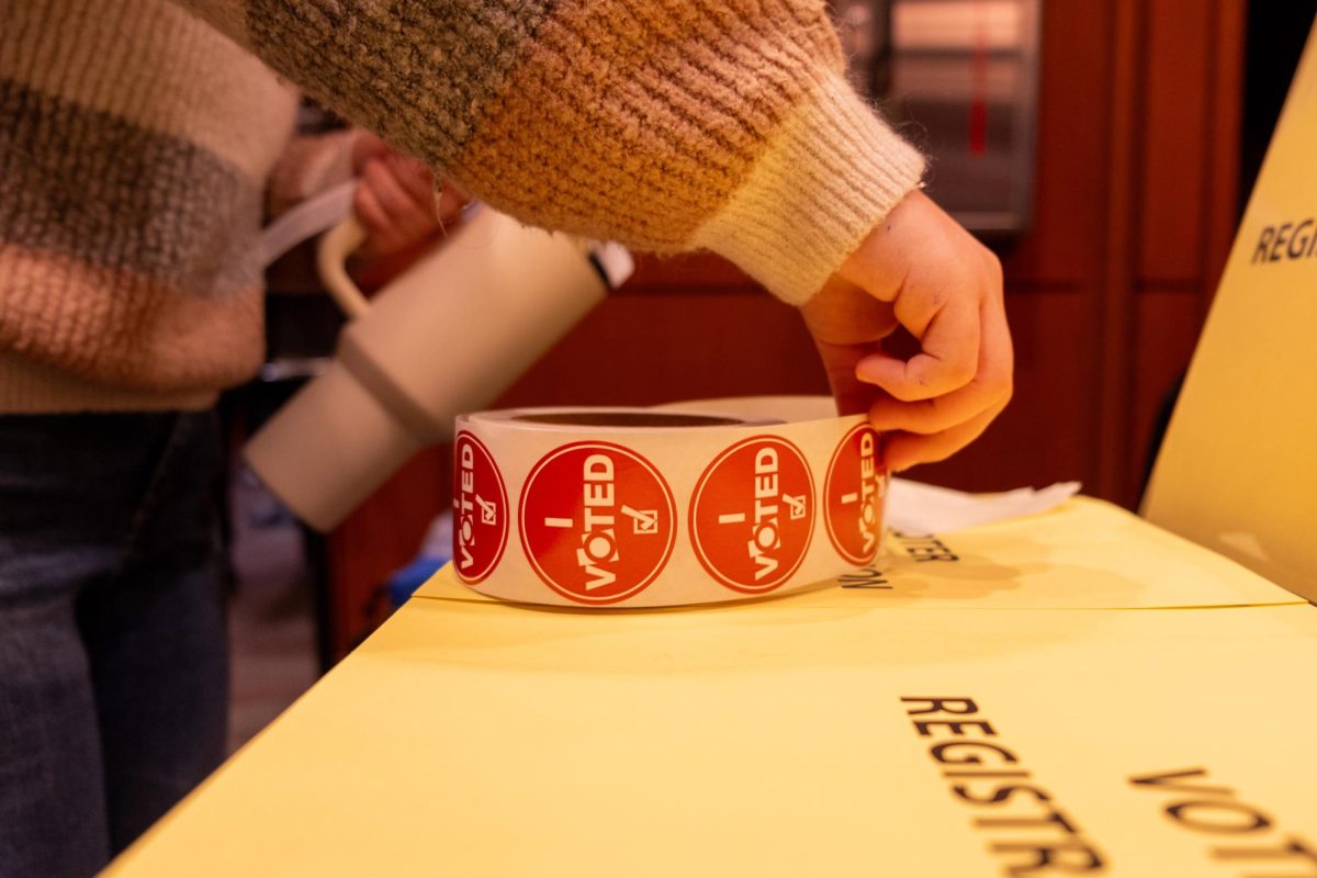 A University of Utah student grabs a sticker after voting at the J. Willard Marriott Library in Salt Lake City on Tuesday, Nov. 5. (Photo by Madeline Van Wagenen | The Daily Utah Chronicle)