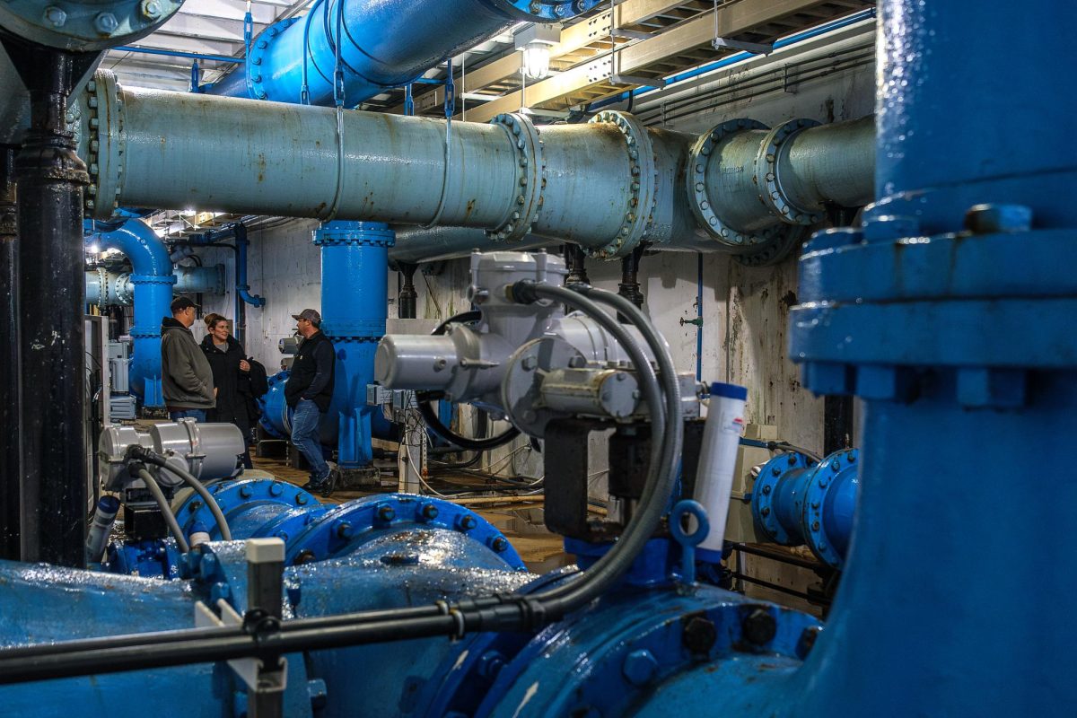 From left, Russ Ranck, Chloe Morroni and Dustin Gilgen converse with each other while surrounded by large pipes that transport filtered, potable water at the Big Cottonwood Water Treatment Plant in Cottonwood Heights, Utah, on Tuesday, Dec. 10, 2024. (Photo by Marco Lozzi | The Daily Utah Chronicle)